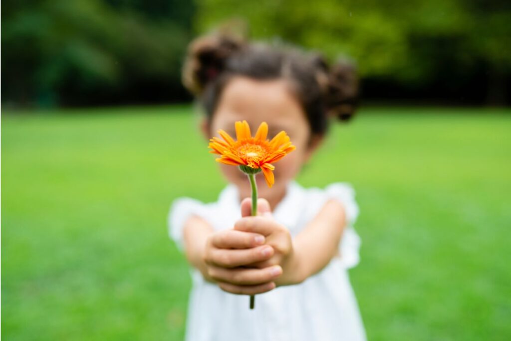 társas támasz - kislány virággal a kezében